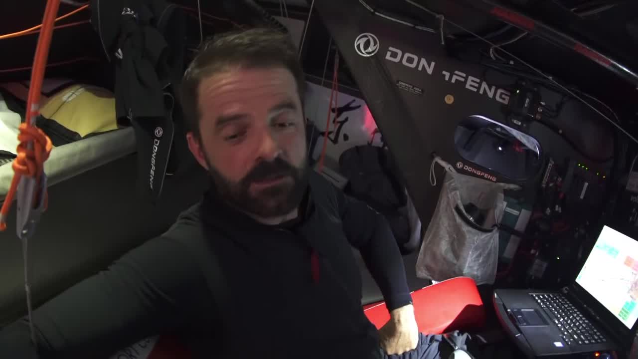 Pascal, at the nav station, talks about the last 100 miles to Cape Town. Standing in the cabin hatch, Stu talks about one time coming into Cape Town having a breakdown at the end that almost cost them a position. He sprays fresh water from a drinking bottle onto his face. Stu: "That is beautiful." Slomo shots of the cockpit: Carolijn trimming a line, Pascal (?) looking thoughtful, taking a line off the pit winch. Loud wind audio; mast cam view of two crew working on the bow in the spray. Looks like changing down to the J2, maybe? Bow cam shot, looking aft, of the new sail unfurling. Crew pulling the old sail, bagged, off the bow. Stern cam view, looking forward, with reefed (double-reefed?) main and crew at the mast. Grinding. Charles on the helm. Spray.