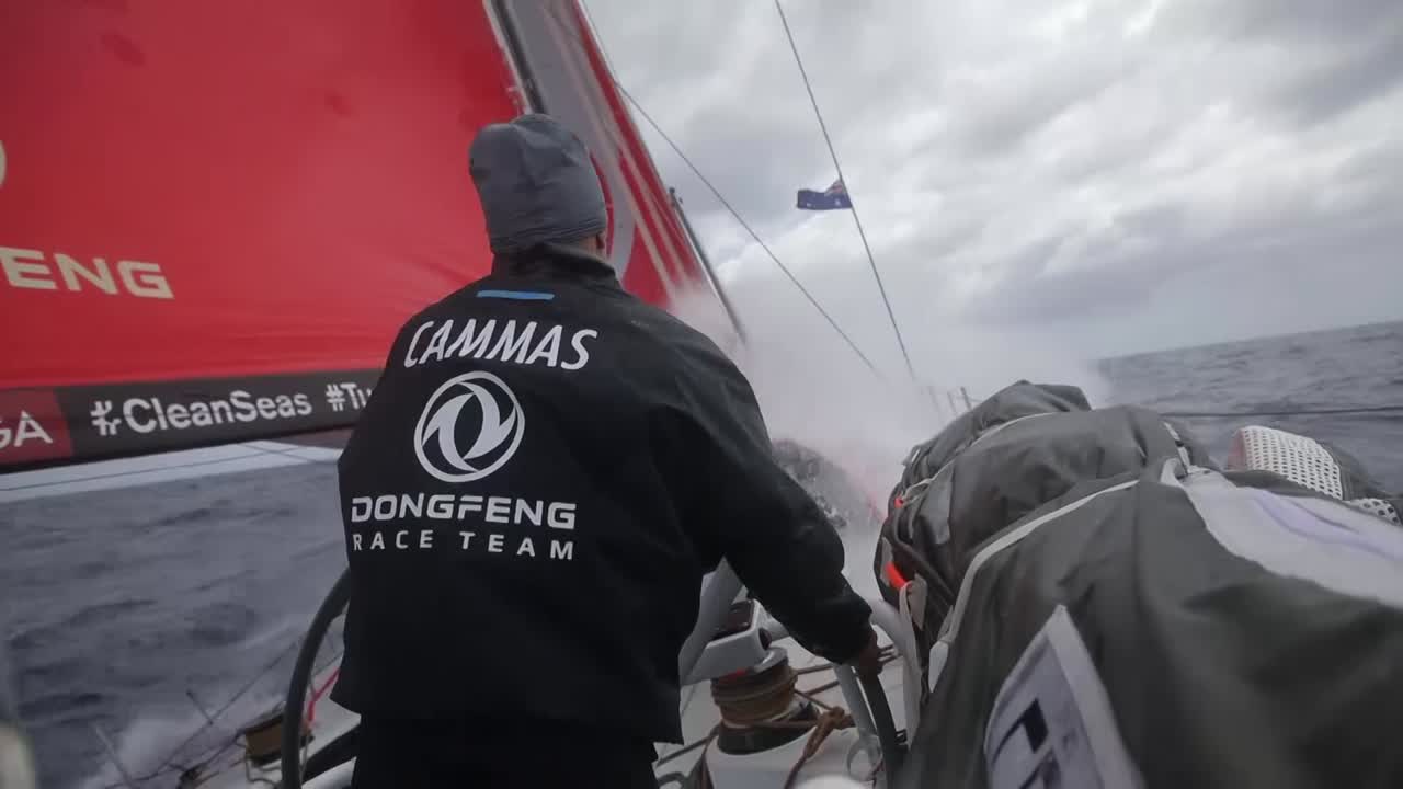Spray on deck. Franck on the helm. Then at the nav station, he explains that the sched was good for them. Now they have a big gap (to second and third). Following their plan. On deck, Jack on the helm. Below, Horace talks about trying to fight for the lead on the second day out of Melbourne. Close to shore, lots of maneuvers. Shots of stacking the sails aft for a gybe. Stacking below. Spray. Sunset.