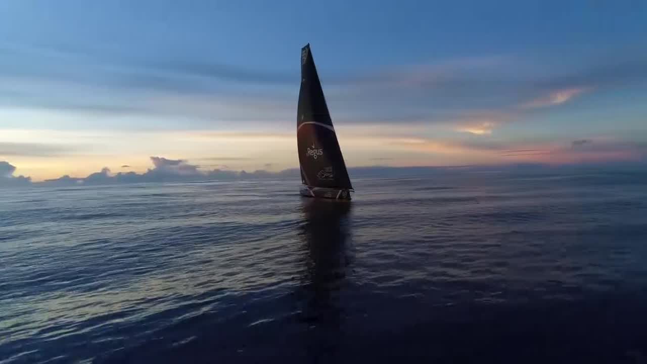 Mostly dark sky. Drone shots of Scallywag sailing in the doldrums. Alex below. Libby and Witty below at the nav station, checking a sched. Libby: "Made gains on the fleet. Fastest boat; going a whole 4 knots." Drone shot of sunrise. Witty: "We're worried about finding a passing lane between here and Hong Kong. Because we can't finish here into Hong Kong." Libby talks about another 250 miles of light stuff. Annemieke in the bow: "Boring!" Annemieke in the bow. Alex talks about his messy roommate, Bessie. Talks about the heat, difficulty sleeping. Shot of crew sleeping on the bow. Annemieke talks about the difference when they're moving vs. when they're not. She feels like they're doing well.